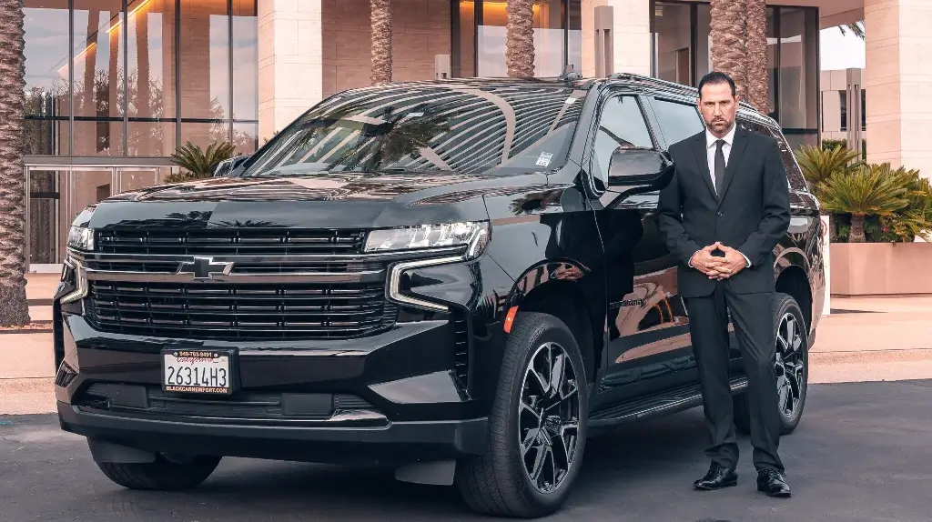 Image of a Chevrolet Suburban and a chauffeur standing next to it, somewhere on the streets of Newport beach, CA region.